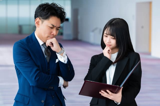 悩むスーツの男女