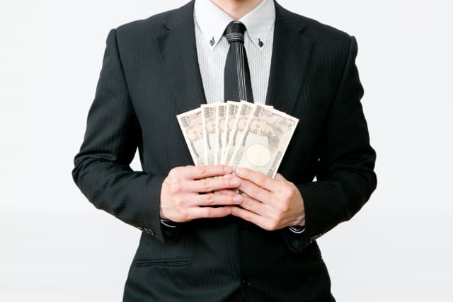 お金を持つスーツの男性