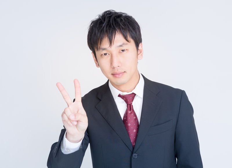 指を2本立てる男性